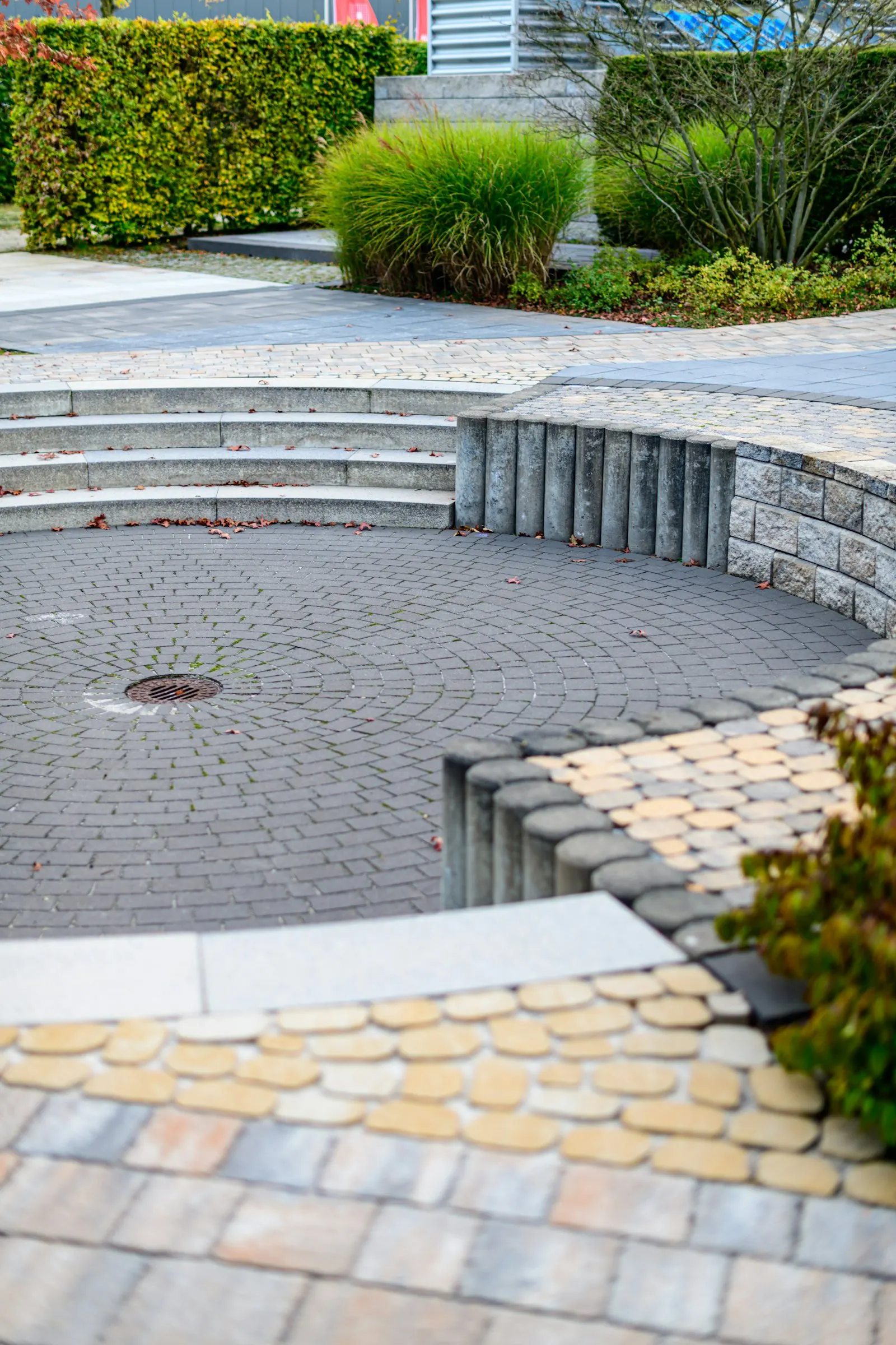 Curved paver patio with seating wall and greenery